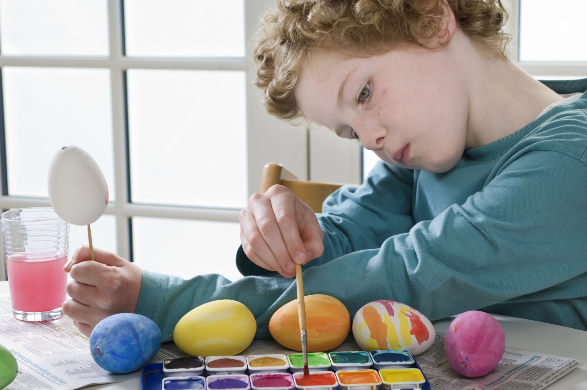 Et barn ca 7 år maler på egg i påsken