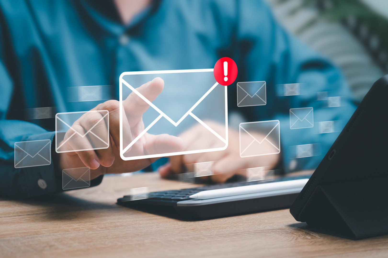 En epost  som er digital henger i luften med et utropstegn på. Det er en håns som trykker på den